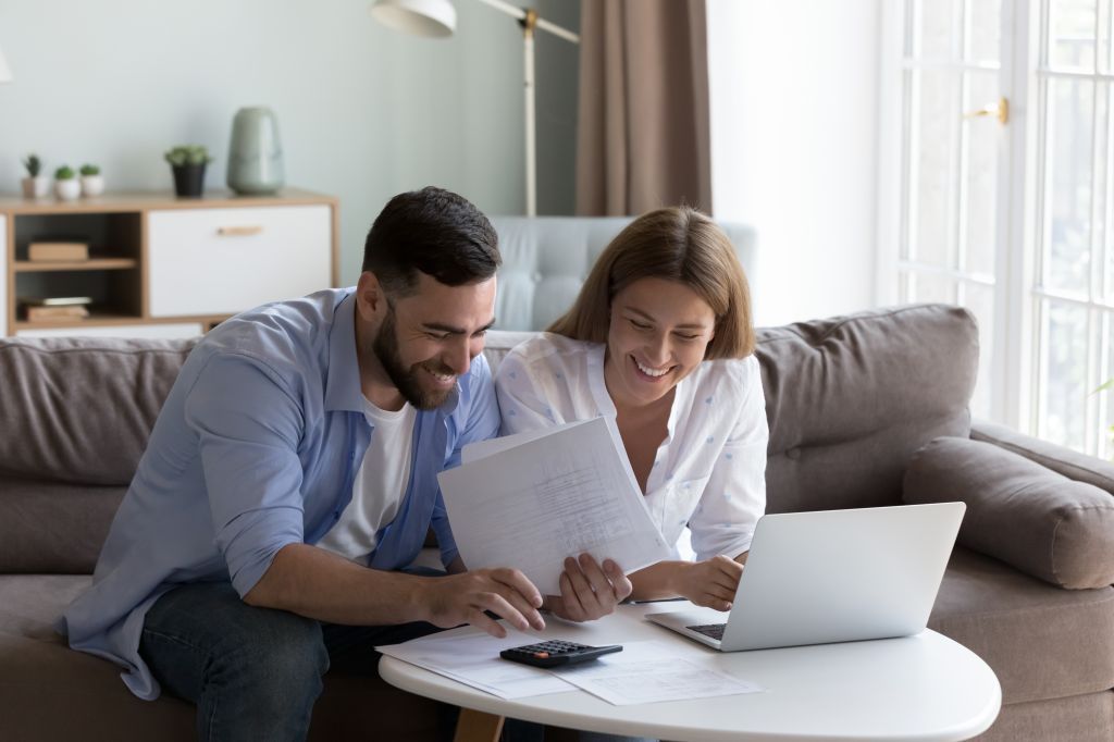 A couple doing calculations on a calculator and holding a paper.